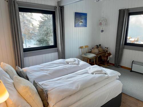 two beds in a room with two windows at Magnifique Maison près du centre in Nendaz