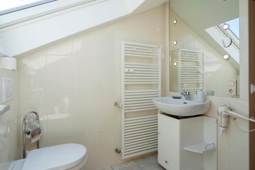 a white bathroom with a sink and a toilet at Dorfwirt Pfronten in Pfronten