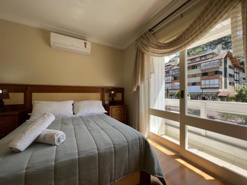een slaapkamer met een bed en een groot raam bij Morada da Montanha Centro by Achei Gramado in Gramado