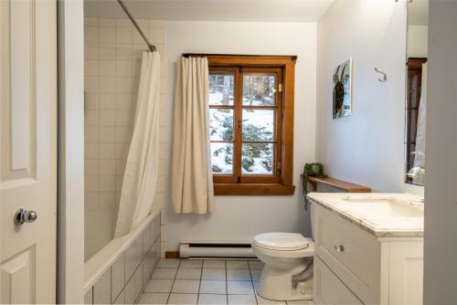 La salle de bains est pourvue de toilettes et d'une fenêtre. dans l'établissement Chalet du Sous-Bois By My Tremblant Location, à Saint-Faustin–Lac-Carré