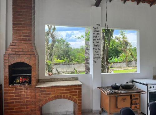 sala de estar con chimenea de ladrillo y ventana en Chalé em Pousada Recanto MD, en Itaboraí