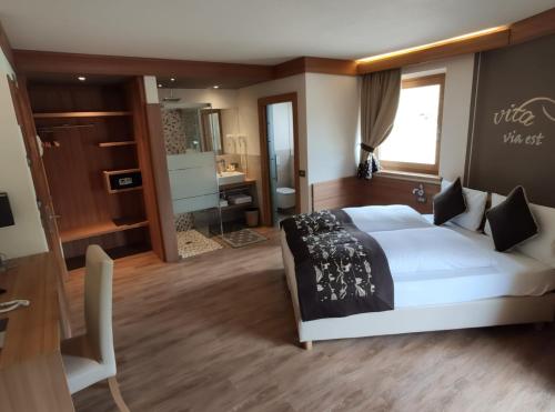 a bedroom with a large white bed and a bathroom at Hotel Bondi in Livigno