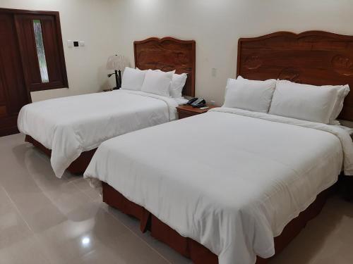 2 camas en una habitación de hotel con sábanas blancas en PESHERES INN & SPA en Bon Accord