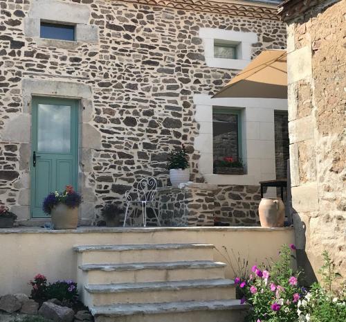 a stone building with a green door and stairs at Chambres d'Hôtes Maison Balady in Bellenaves