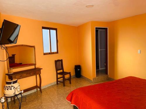 a bedroom with orange walls and a bed and a mirror at Hotel Posada Victor Antonio in Zacatlán