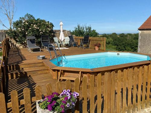 a pool on a wooden deck with chairs and a table at Chambres d'Hôtes Maison Balady in Bellenaves