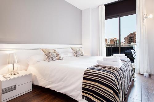a white bedroom with a white bed and a window at Suites4days Provenza Apartment in Barcelona