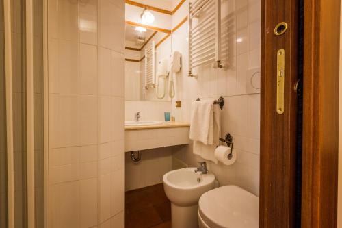 Baño blanco con aseo y lavamanos en Hotel 4 Coronati, en Roma