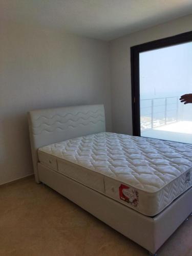 a bed in a bedroom with a large window at Ferienhaus mit Meerblick in Bodrum City