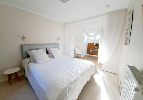 a white bedroom with a white bed and a table at Les gîtes du clos des pradals in Tarascon-sur-Ariège