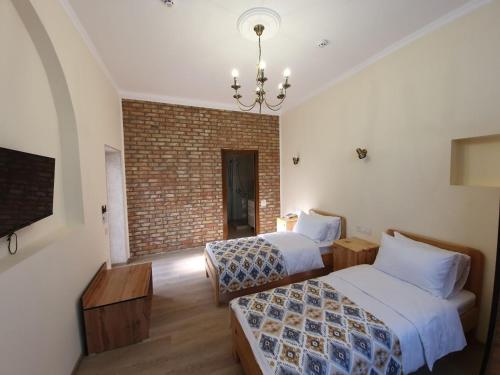 a bedroom with two beds and a brick wall at Chorsu Inn in Tashkent