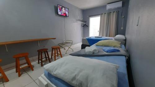 Habitación hospitalaria con 2 camas y mesa en ZZZ BRUNO KLEMTZ - Residencial Recanto dos Pássaros Estúdio até 4 pessoas com ar Split wifi coz vaga, en Itapema