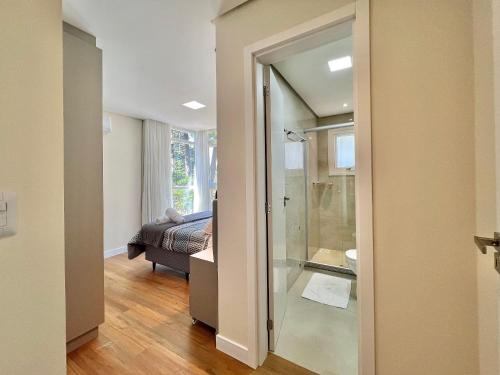 un baño con una puerta de cristal que conduce a un dormitorio en Apartamento Garten Haus 2 suítes by Achei Gramado, en Gramado