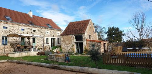 an old stone house with a wooden fence at Chambres d'Hôtes Maison Balady in Bellenaves