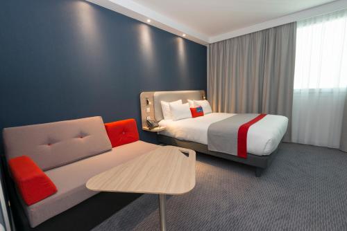 ヴェリジー・ヴィラクブレーにあるHoliday Inn Express Paris - Velizy, an IHG Hotelのベッドとソファ付きのホテルルーム