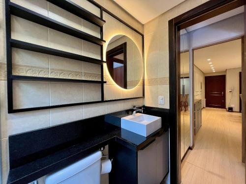 y baño con lavabo y espejo. en Apartamento Morada dos Tucanos 1 dorm by Achei Gramado, en Gramado