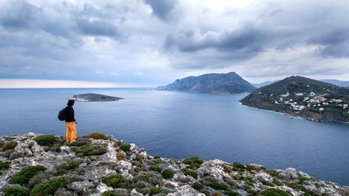 a man standing on top of a mountain overlooking the ocean at Aegean Villa-On beach apartment! Ideal choice! in Masouri