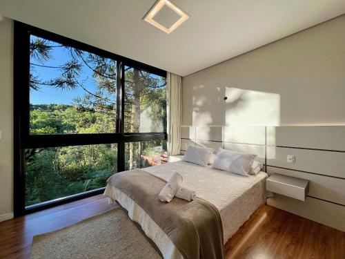 1 dormitorio con cama y ventana grande en Incrível Casa Araucária 3 Suítes by Achei, en Canela