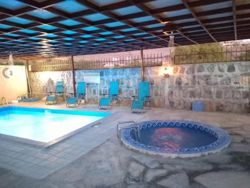 a pool with chairs and a hot tub in a room at The Wadi Inn in Al Ḩamrāʼ