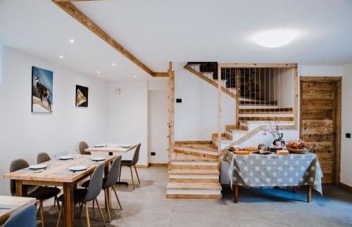 a dining room with tables and chairs and a staircase at Atelier della Montagna in Zambla Alta