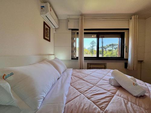 um quarto com uma grande cama branca e uma janela em Casa Allegro 3dorm prox Lago Negro by AcheiGramado em Gramado