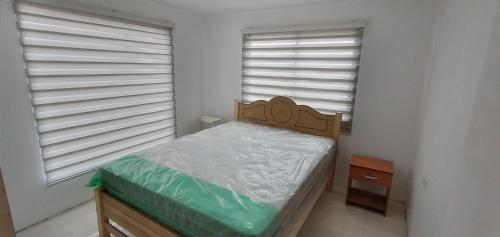 a small bedroom with a bed and two windows at Casa mediterranea santo domingo in Santo Domingo