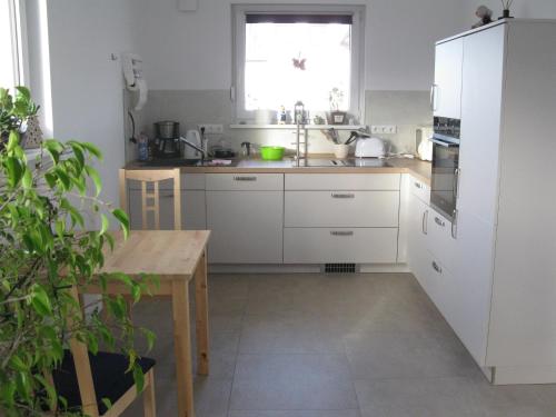 a kitchen with white cabinets and a table and a window at FeWoMeißner in Wittingen