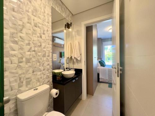 y baño con aseo blanco y lavamanos. en Apartamento Aire 1 dorm by Achei Gramado, en Gramado