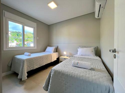 2 camas en una habitación pequeña con ventana en Apartamento Res Aire 2 dorm by Achei Gramado, en Gramado