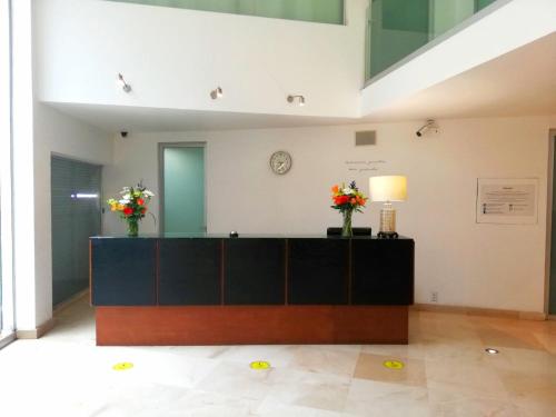 a reception desk in a room with flowers on it at Suites Teca Once in Mexico City