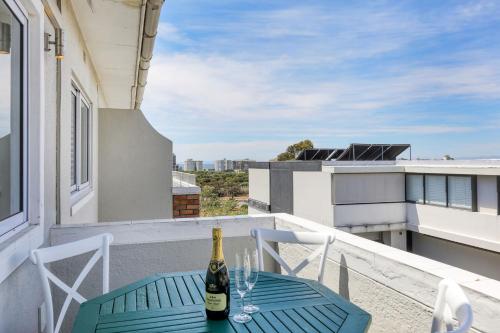 Una botella de vino en una mesa en un balcón en Backup-Powered Elegant Promenade Retreat, en Ciudad del Cabo