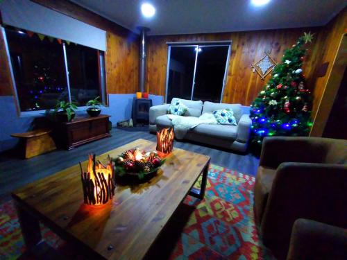 Hostal Ruka Lodge في فيلاريكا: غرفة معيشة مع شجرة عيد الميلاد وطاولة قهوة