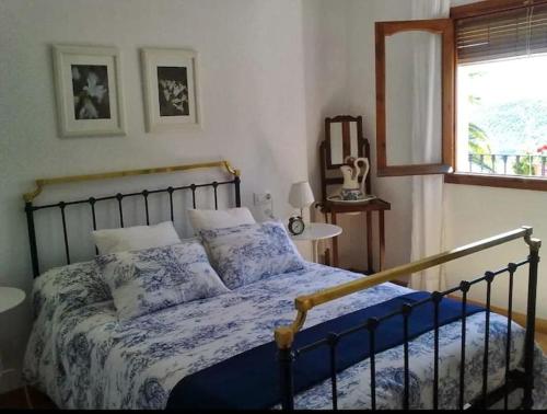 Schlafzimmer mit einem Bett mit blauer Bettwäsche und einem Fenster in der Unterkunft La Villa, Alojamiento Rural in Iznájar