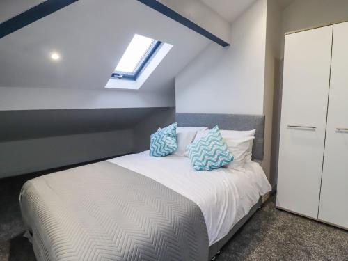 1 dormitorio con 1 cama con almohadas azules y blancas en Mill Hey, en Keighley