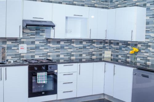 a kitchen with white cabinets and a stove top oven at Carsi holiday Villa in Lusaka