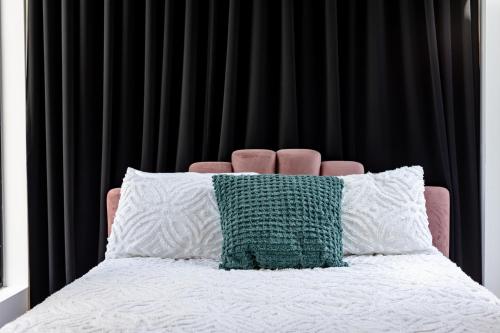 Una cama con una almohada verde y blanca. en Le Virtuose - Vieux-Terrebonne, en Terrebonne