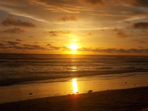 a sunset on a beach with the ocean at The Gunjur Project Lodge in Gunjur