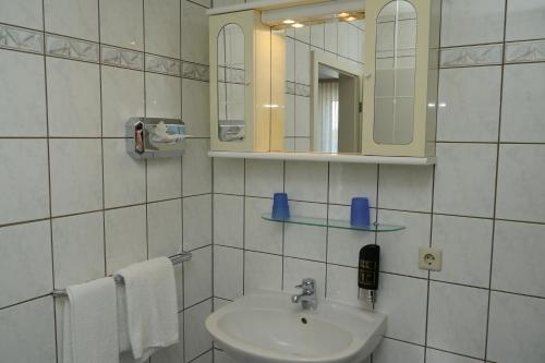 a bathroom with a sink and a mirror and towels at Erbenholz Hotel in Hannover