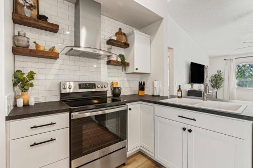 a kitchen with white cabinets and a stove and a sink at Nampa Sugar House, near walking paths wHOT TUB! in Nampa