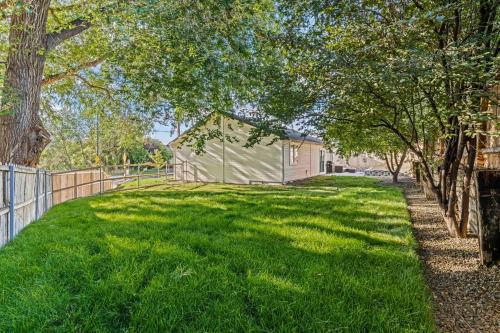 a yard with a fence and green grass and trees at Nampa Sugar House, near walking paths wHOT TUB! in Nampa