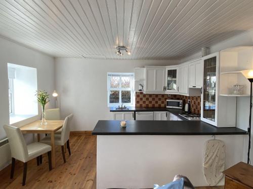 eine Küche mit weißen Schränken sowie einem Tisch und Stühlen in der Unterkunft Cottage 433 - Ballyconneely in Ballyconneely