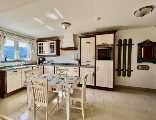 eine Küche mit einem Tisch und Stühlen sowie eine Küche mit weißen Schränken in der Unterkunft Landhaus-Chalet-Keilberger Blick in Kurort Oberwiesenthal