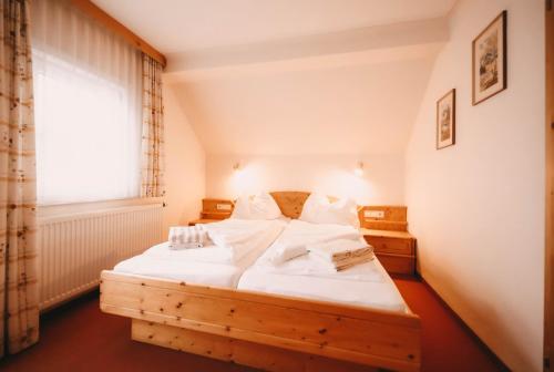 a bedroom with a wooden bed with white sheets and a window at Posers Bergwelt B&B in Schladming