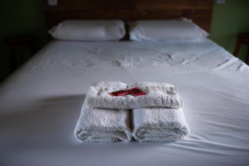 uma pilha de toalhas numa cama com uma fita vermelha em Pousada Bela Vista do Ismail - Lapinha da Serra em Santana do Riacho