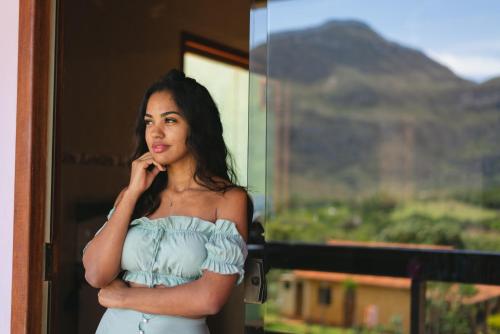 a woman in a blue dress talking on a cell phone at Pousada Bela Vista do Ismail - Lapinha da Serra in Santana do Riacho