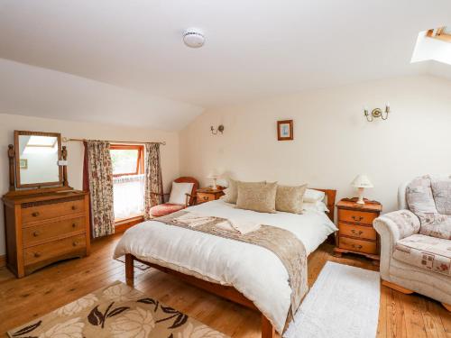um quarto com uma cama, um espelho e uma cadeira em Clare's Cottage em Grainthorpe