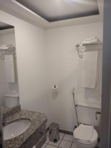 a bathroom with a toilet and a sink at Bristol Praia do Canto Apart Hotel in Vitória
