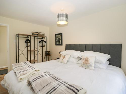 1 dormitorio con 1 cama con sábanas y almohadas blancas en Orchard House Cottage en Malmesbury