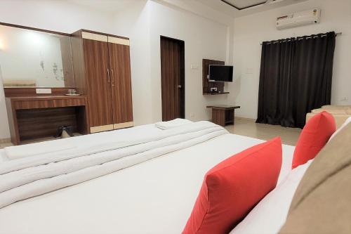a bedroom with a large white bed with red pillows at Hotel Om Inn - Talegaon Dabhade in Talegaon Dābhāde