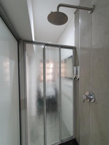 La salle de bains est pourvue d'une douche avec une porte en verre. dans l'établissement Unit 26, Genesis, à Johannesbourg